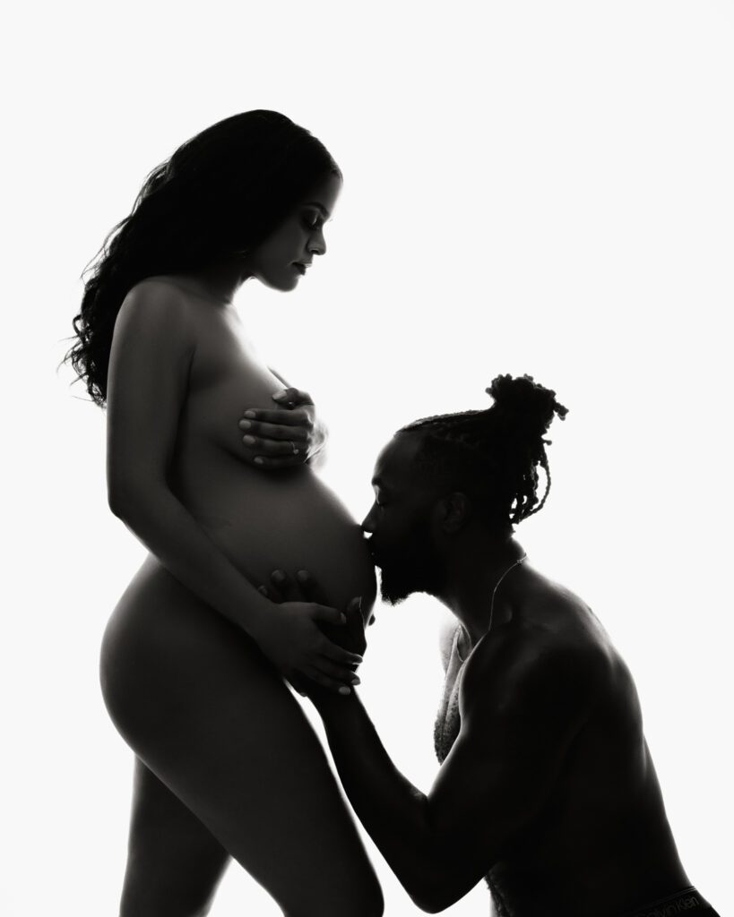Dad kissing pregnant wife's belly as Mom looks down at her husband photographed by Marietta Maternity Photographer.