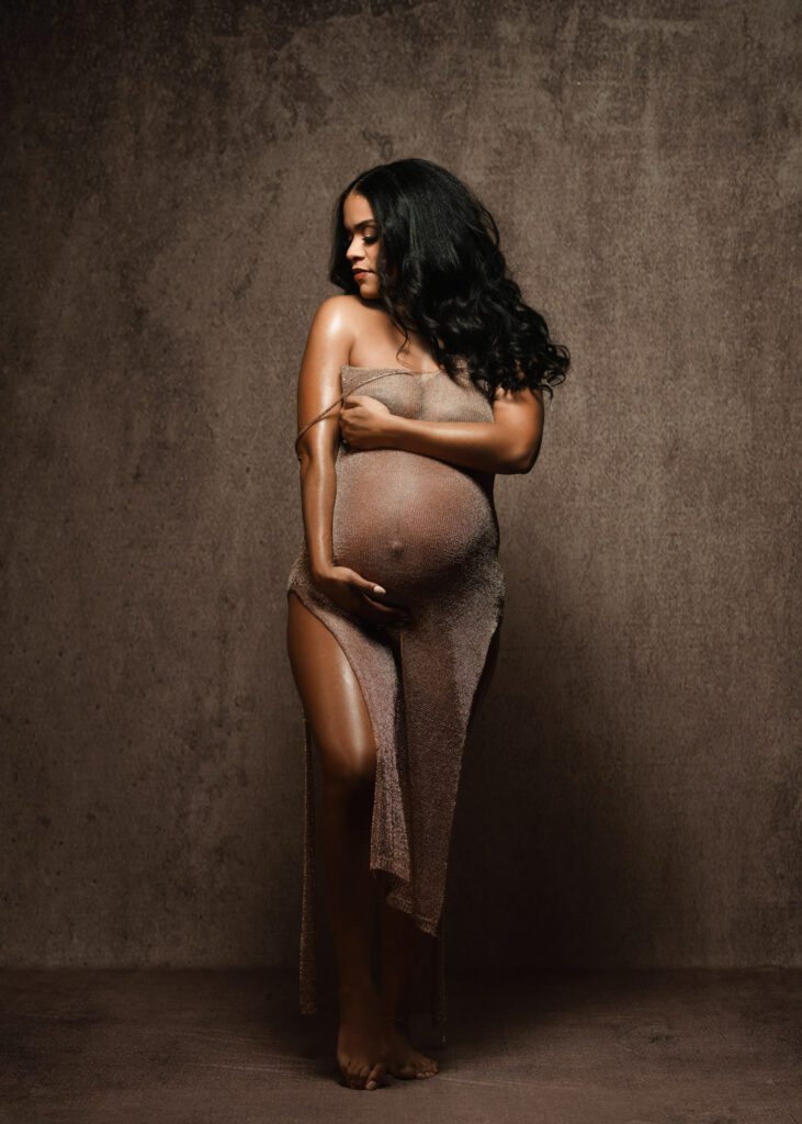 Expecting mother in a bronze gown cradling her belly during a session with a Marietta maternity photographer.