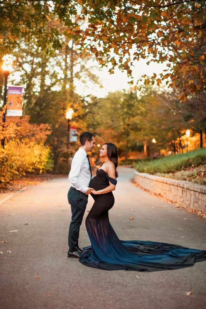 Expecting couple holds hands during Piedmont Park maternity photos with Oak Hill in the background in Atlanta GA.