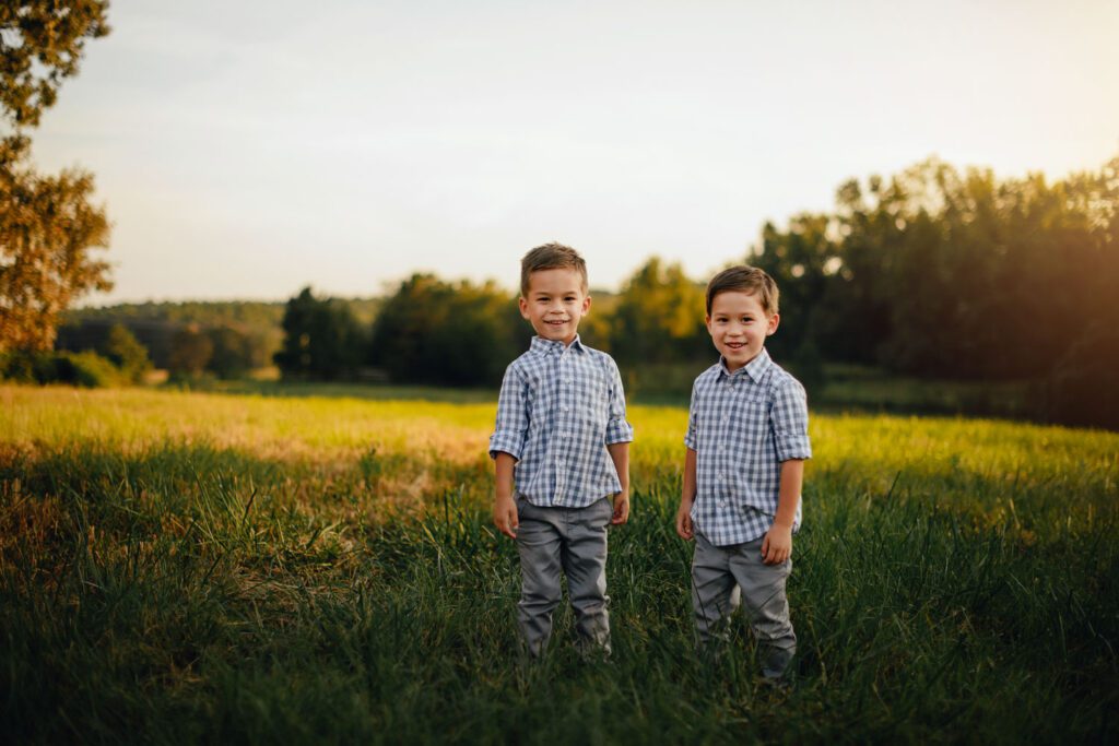 Two brothers standing together with  tall grass meadow in the background