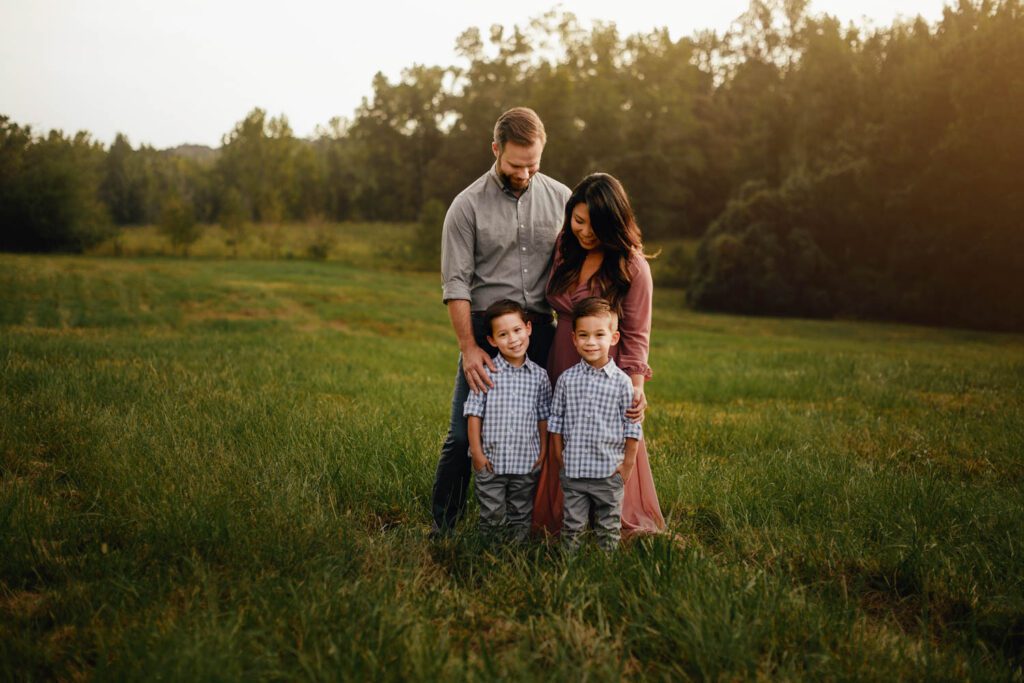 Parents standing behind their two sons with a tall grass meadow in Alpharetta, GA.