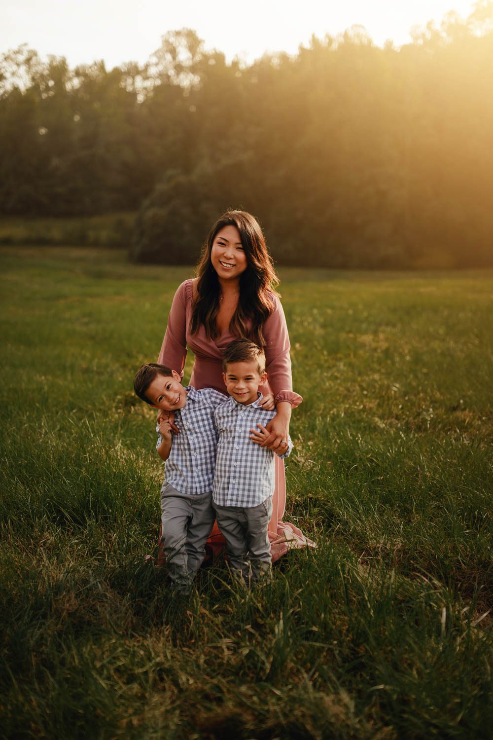 mom with her twin boys in a meadow at sunset with the Garrard Landing Park covered bridge in the background in Alpharetta GA