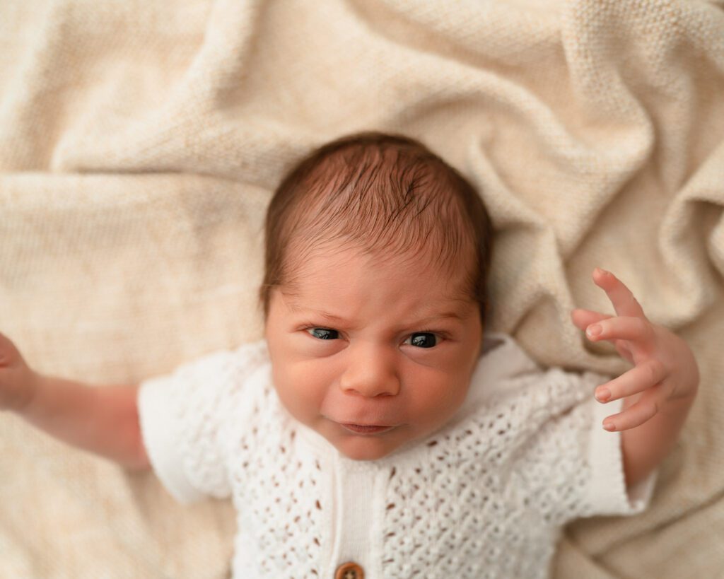 Alpharetta newborn photographer portrait of an alert baby boy looking up with a playful expression.