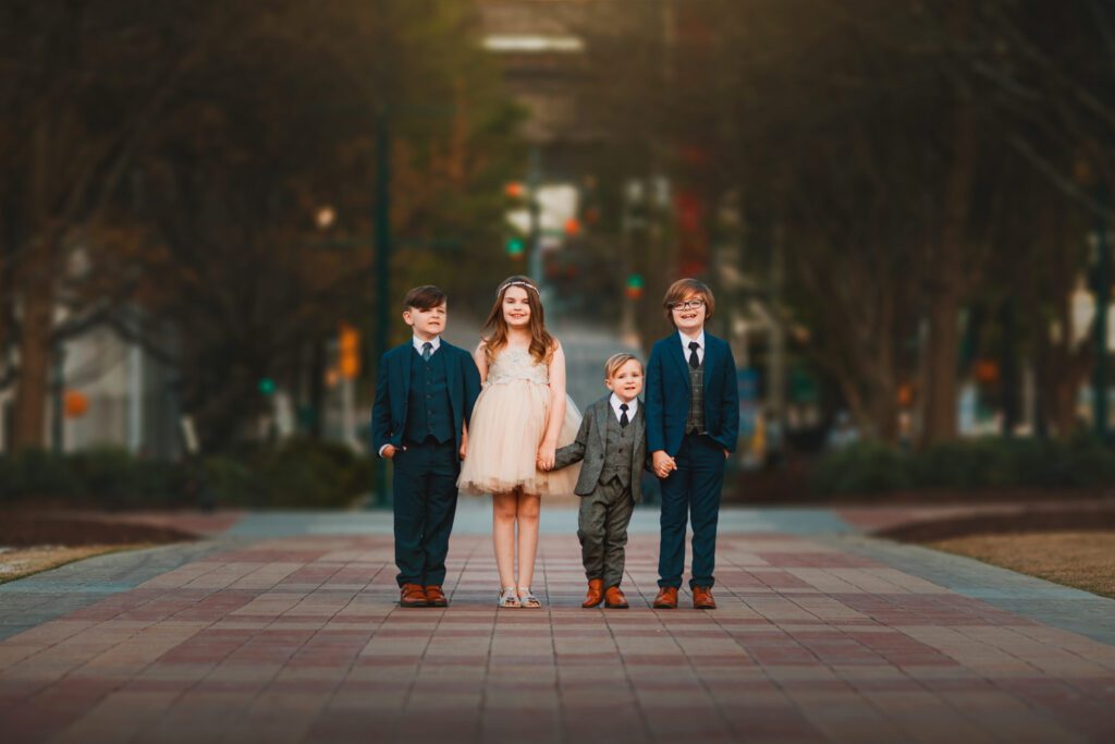 four siblings holding hands in formal attire standing on commemorative brick walkway at Centennial Olympic Park
