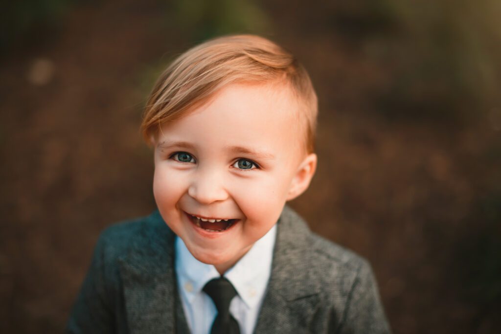 close up of smiling blonde young boy in suit and tie
