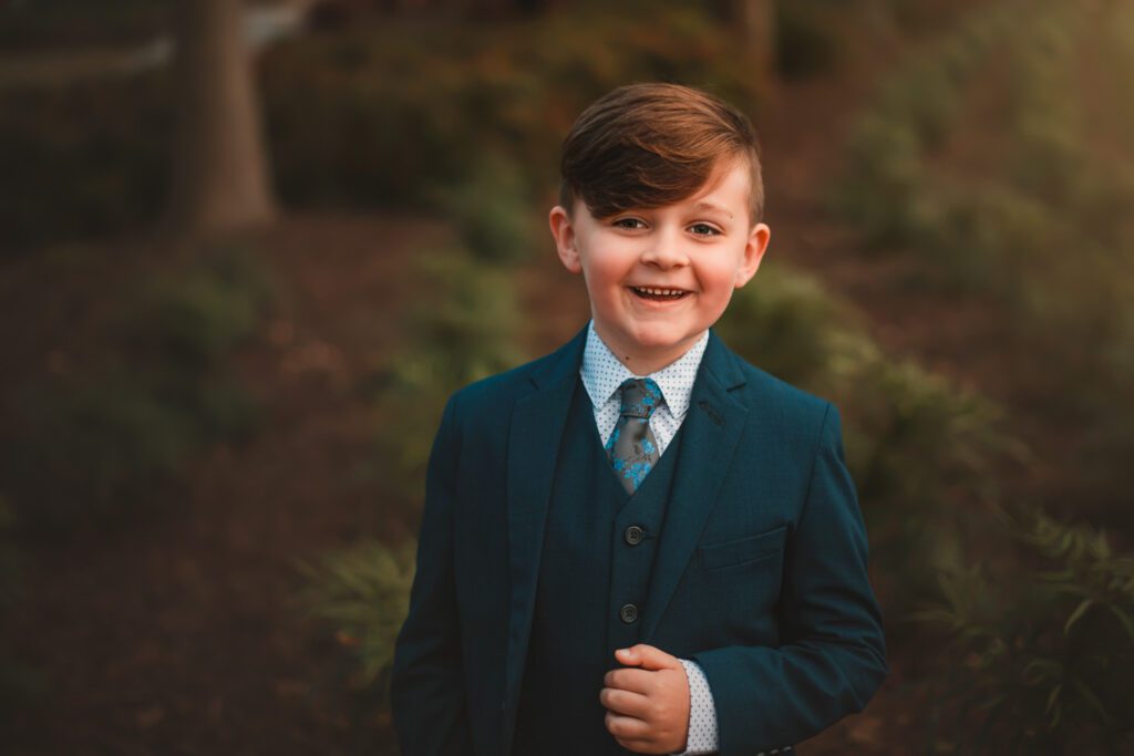close up of tween boy in blue suit and floral tie and vest