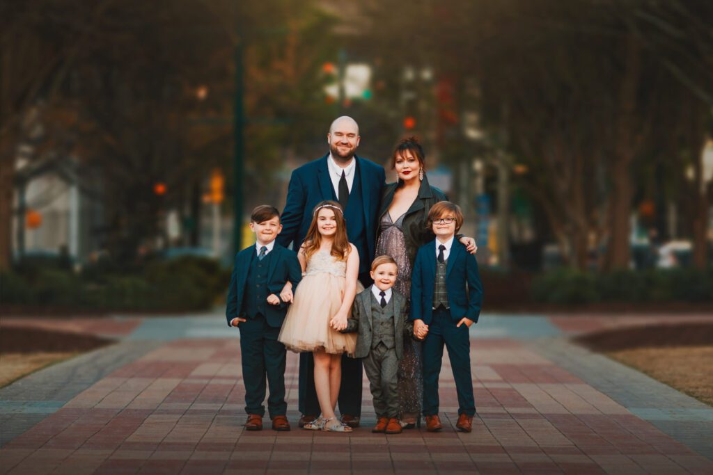 family of six standing closely together on the engraved commemorative brick walkways at Centennial Olympic Park in Atlanta.