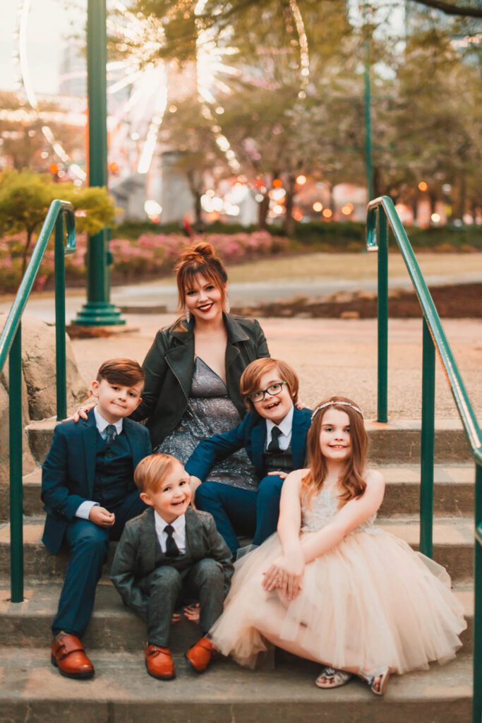 family seated on stairs with the Centennial Olympic Park skyview ferris wheel in the background in Atlanta GA
