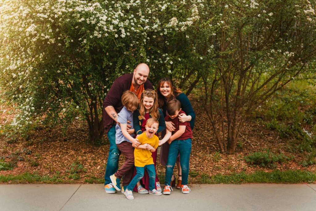 Parents and four children laughing together beneath flowering trees along the Atlanta BeltLine Eastside Trail.