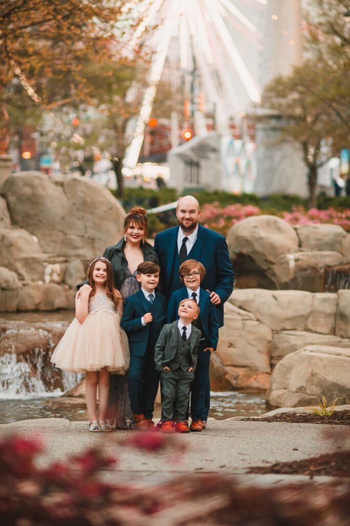 parents standing with four children with the Centennial Olympic Park water gardens in the background in Atlanta, GA
