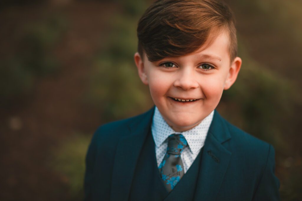 close up of tween boy in formal suit and tie smiling at the camera.