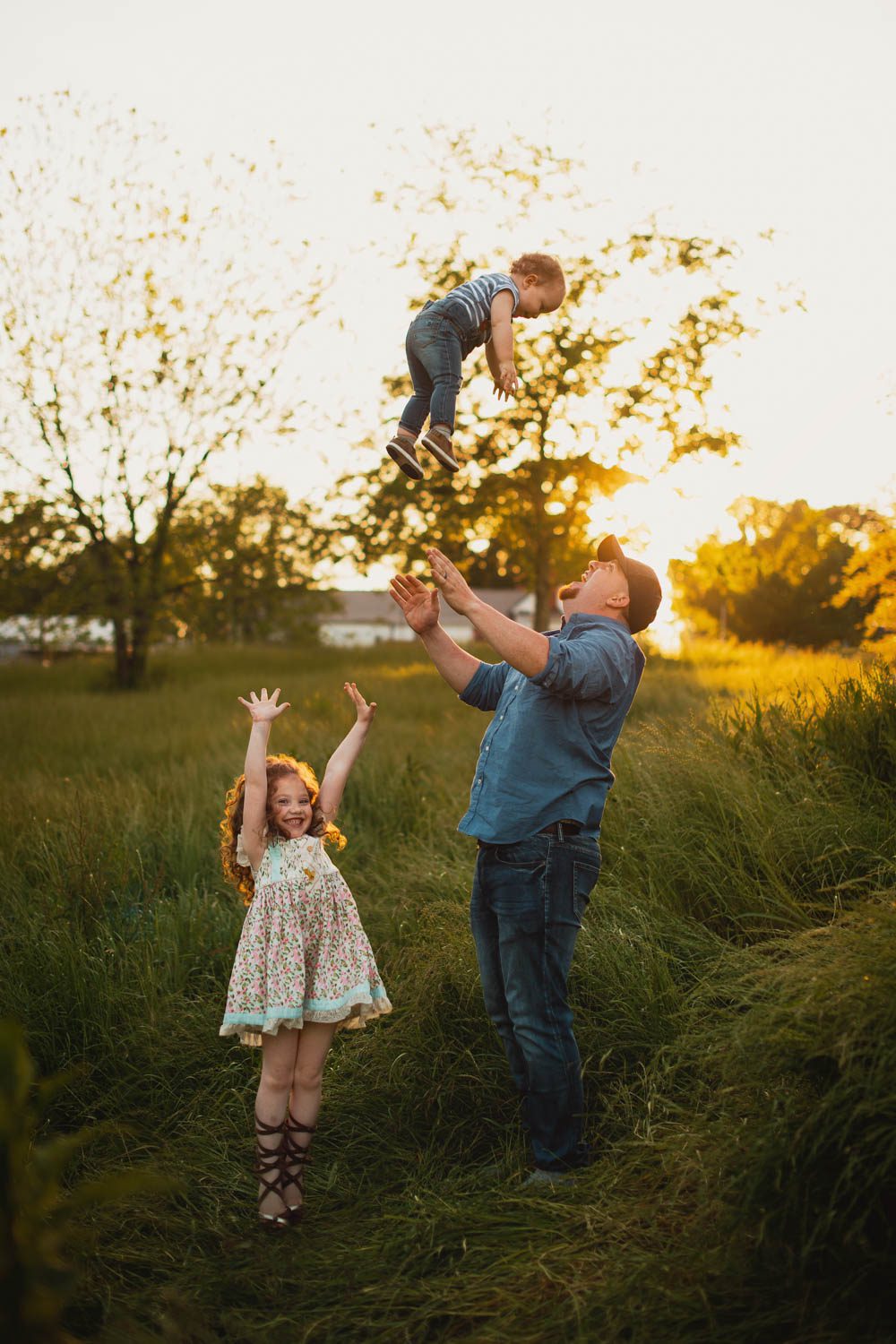 Father tossing son in the air at Cheatham Hill meadow with the historic marble monument in background, Marietta GA