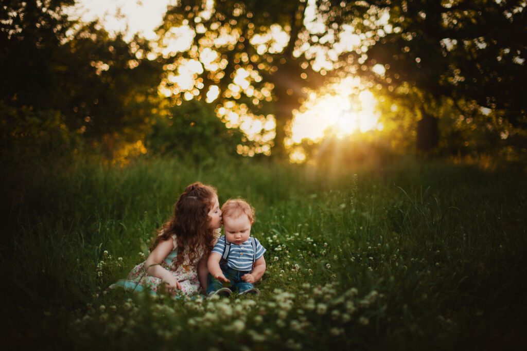 young girl twirling her long ruffled dress and brimmed hat in a meadow at sunset