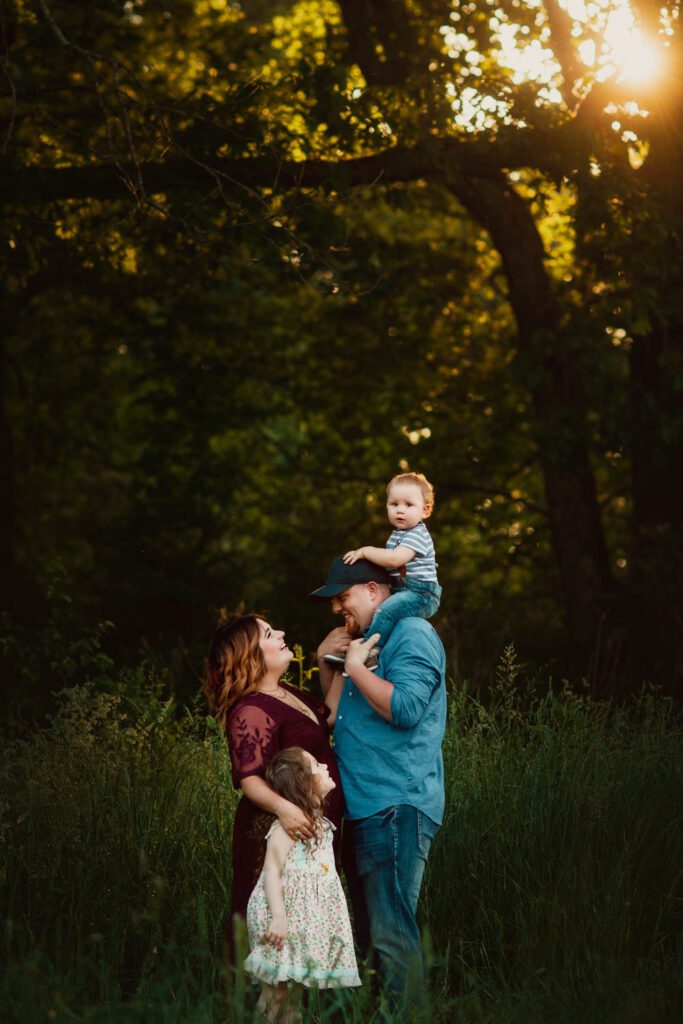 son on dads shoulders as family looks up with split-rail fences in the background at Kennesaw Mountain in Marietta, GA.