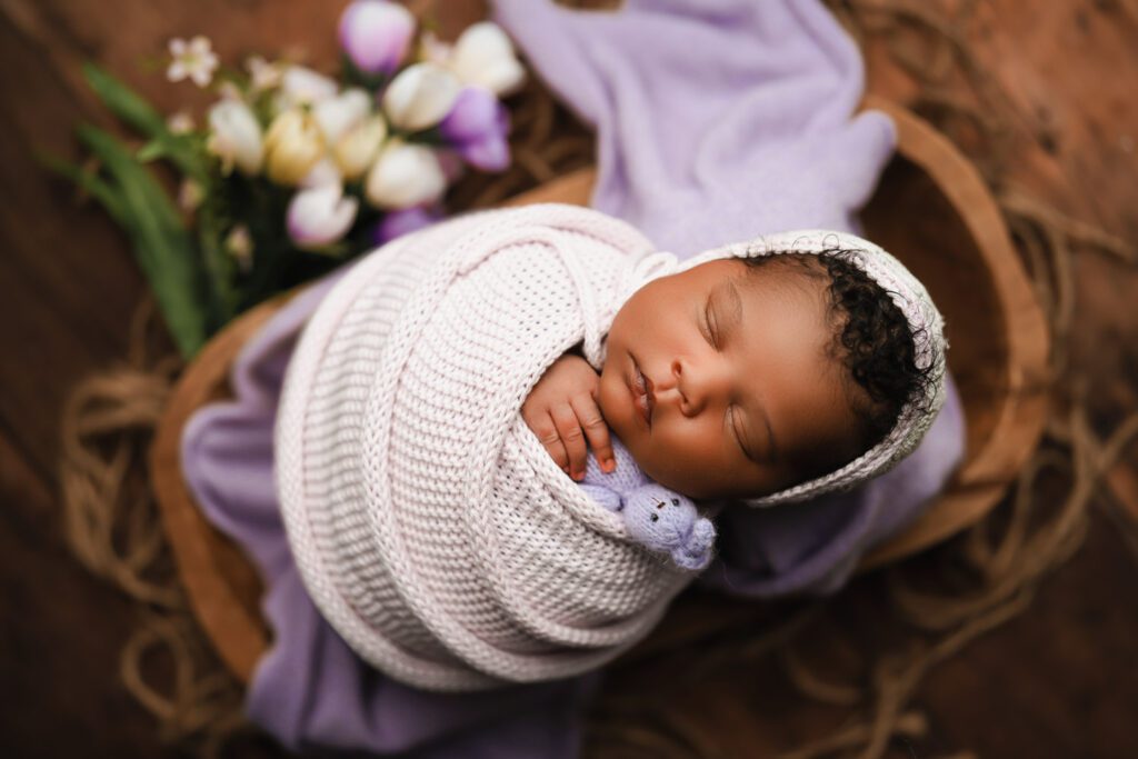 Newborn baby girl swaddled in purple with a matching bonnet and crochet bunny for Marietta newborn photos.