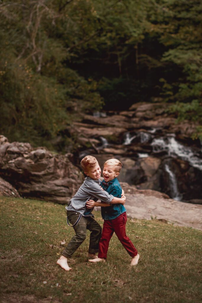 Two brothers playing on the grass with Cochran Mill Falls and broad stone shoals in the background.