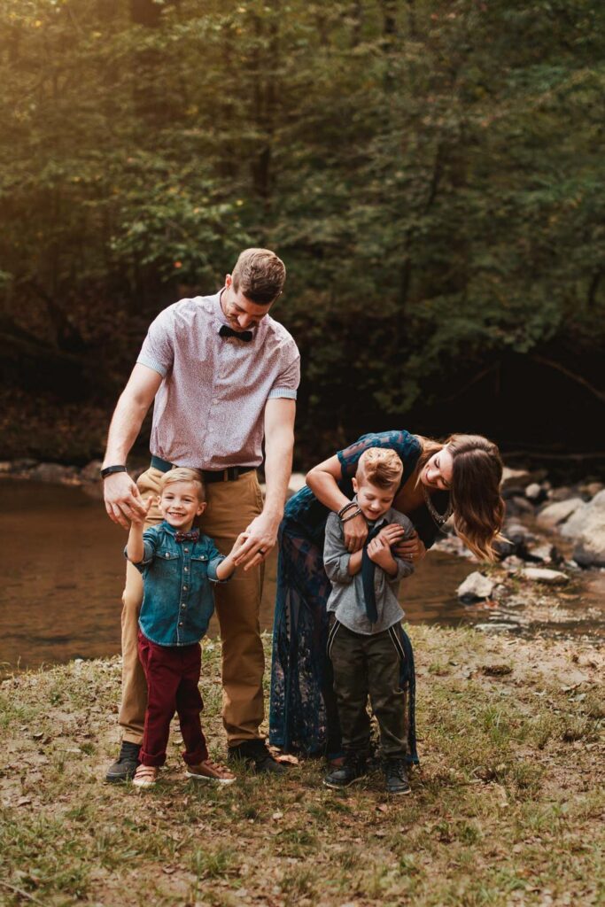 Parents standing with their two sons beside the rocky creek at Cochran Mill Park in Chattahoochee Hills.
