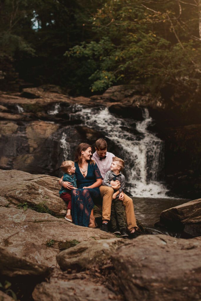 Parents sitting with their two sons out on the shoals with the waterfall in the background.