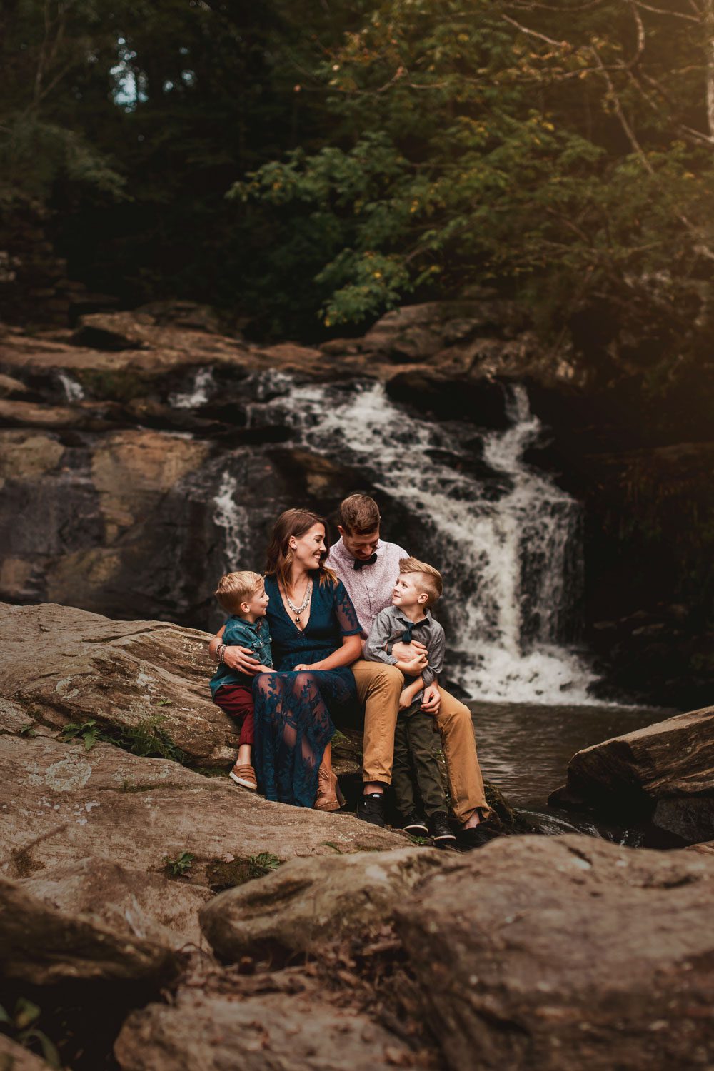 Family sitting on rocks with Cochran Mill Falls waterfall in the background in Chattahoochee Hills, GA.