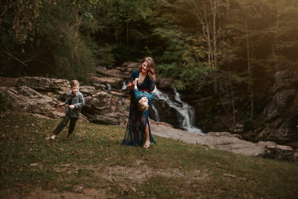 Mom running with her two sons across the grass near the main waterfall at Cochran Mill