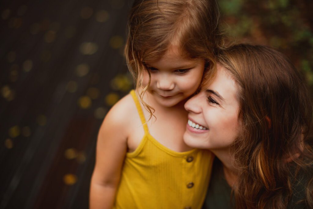 Mom smiling as her daughter leans close to her face