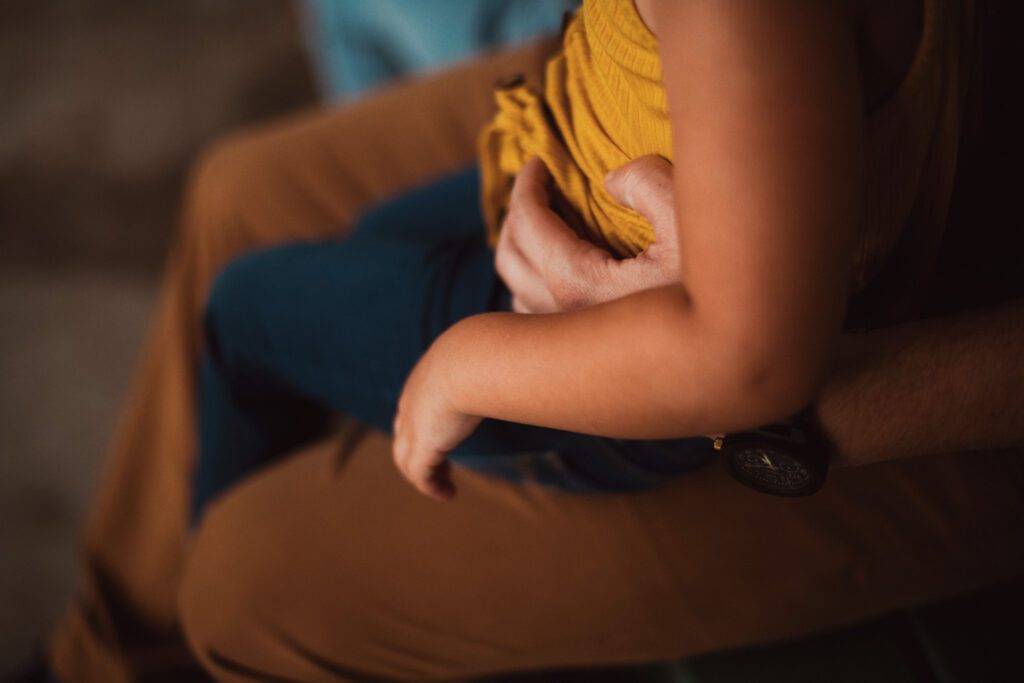 Close-up of a daughter in a mustard top sitting beside dad during a relaxed family portrait