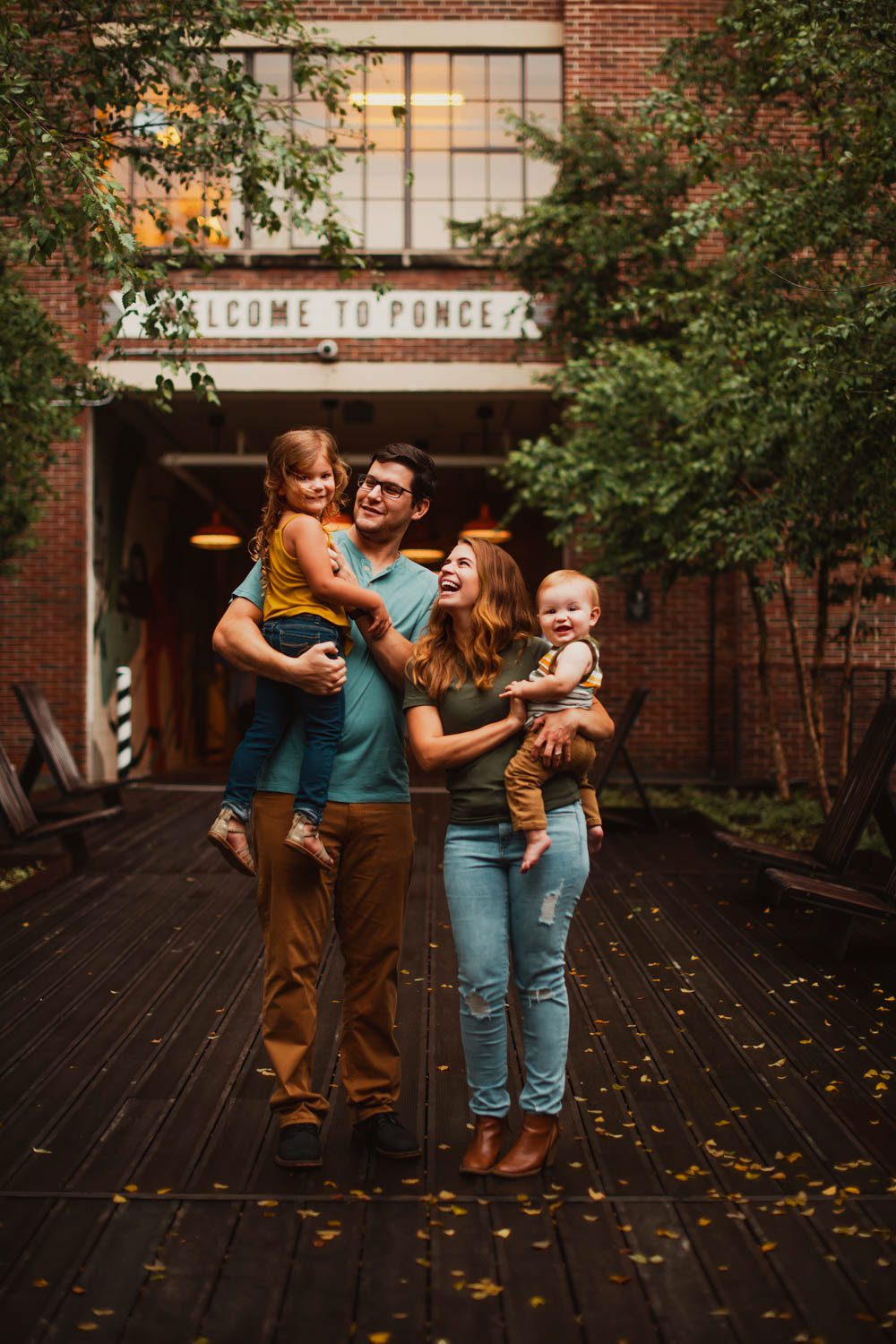 Parents walking with children along the BeltLine bridge with Ponce City Market "welcome to ponce" marquee sign in the background in Atlanta, GA.