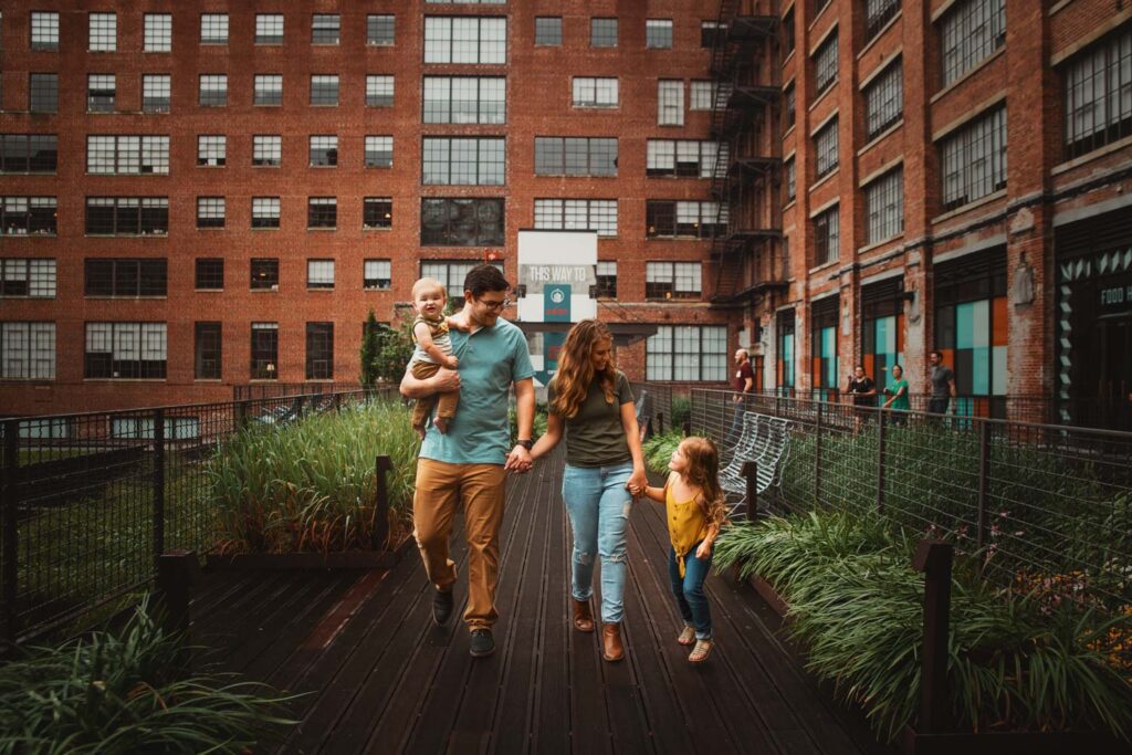 Mom and dad walking with their children beside red brick and original steel-grid windows along the Atlanta BeltLine