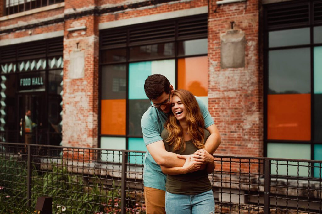 Dad hugging mom outside the 1920s Sears building beside colorful stained-glass-style windows at Ponce City Market.