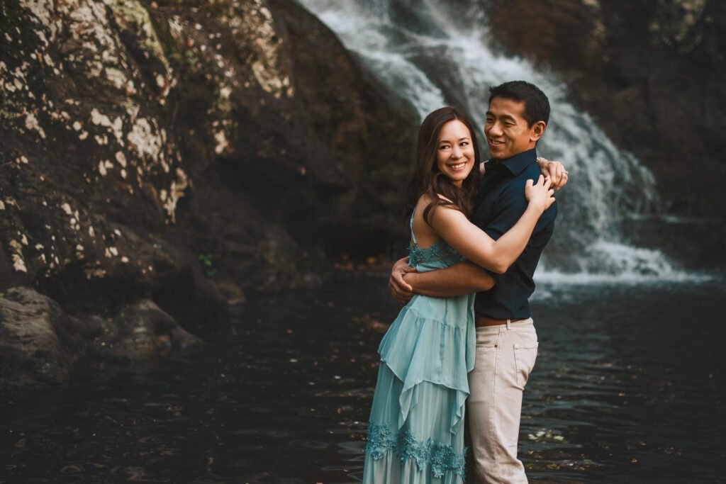 Mom and dad embracing with Roswell Mill waterfall in the background in Roswell, GA.