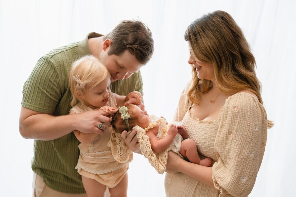 Mom holding her newborn while dad encourages big sister to interact during a Sandy Springs newborn session.