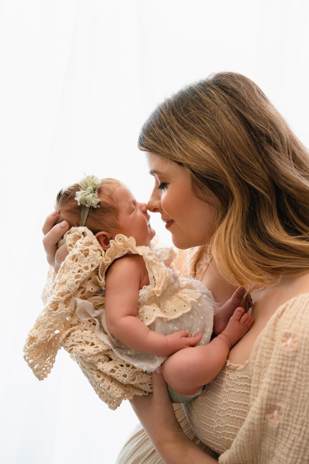 Mom holding her newborn daughter close against a bright white backdrop photographed by Sandy Springs newborn photographer.