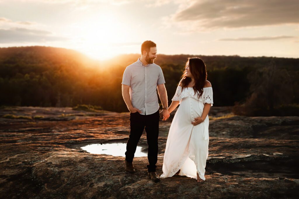 expecting couple looking lovingly at each other at sunset during maternity photos.