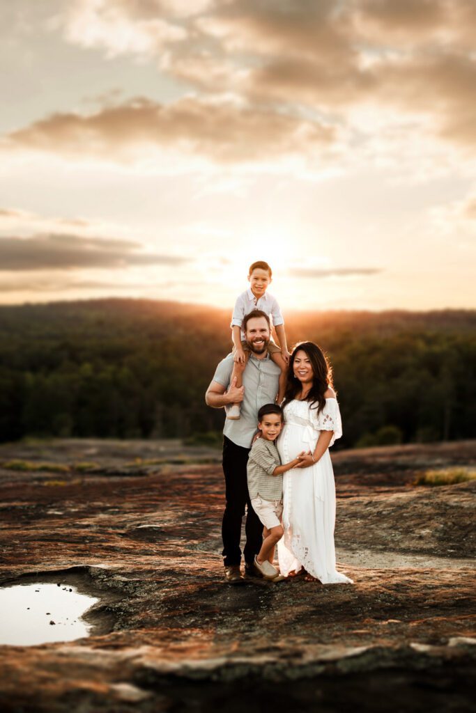 family standing together after a rain storm with Arabia Mountain diamorpha pools in the background in Stonecrest, GA.