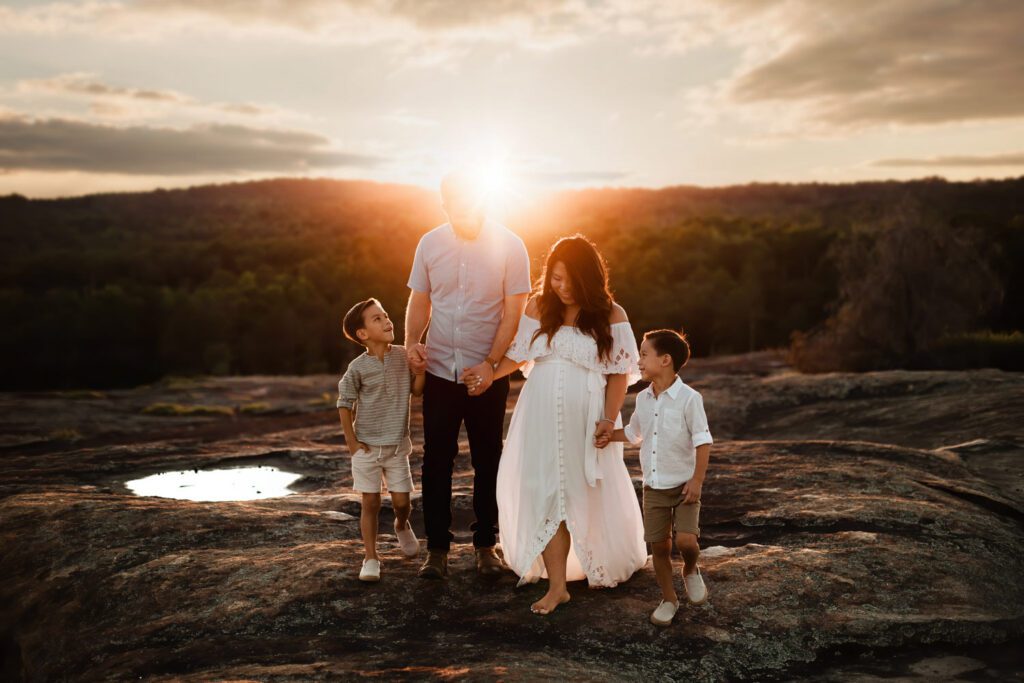 Family holding hands walking together across the crater pools at Arabia Mountain in Stonecrest, GA.
