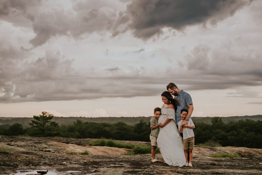 family of four huddled together and hugging on the diamorpha pools at Arabia Mountain during a storm.