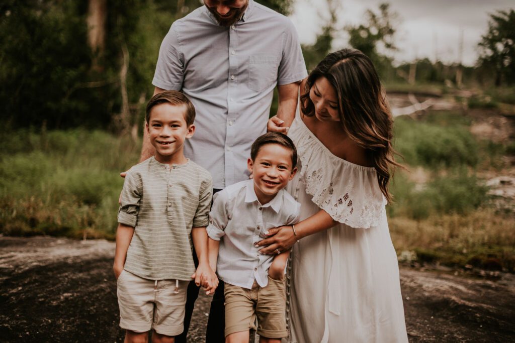 family of four bending down laughing in a forest on stormy day in stonecrest, GA
