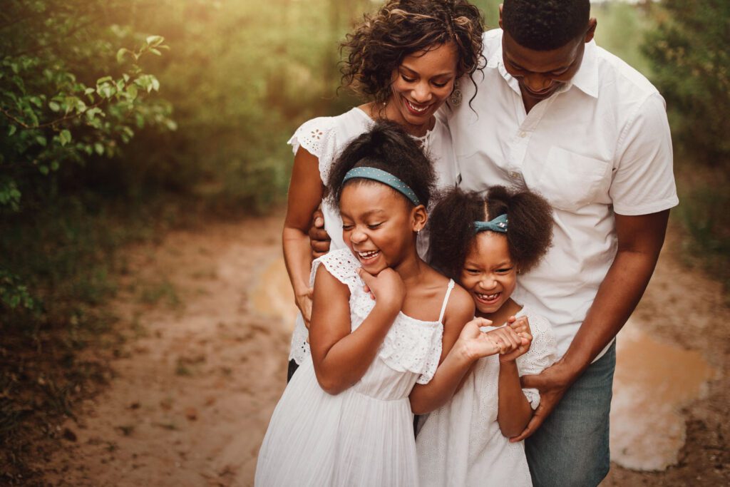 Family in matching white clothes with dad in a white button up shirt and jeans and the girls are wearing white dresses. 