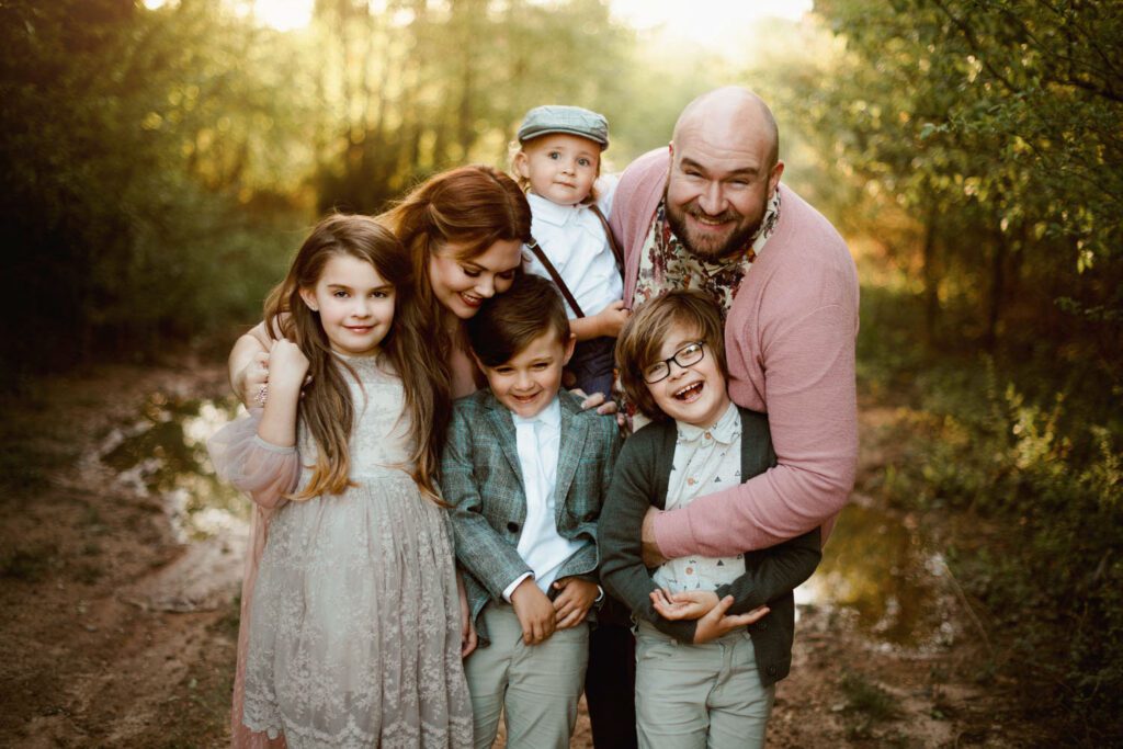 Family huddled together wearing coordinating pink and neutral colored clothes with textures like tweed and lace. 